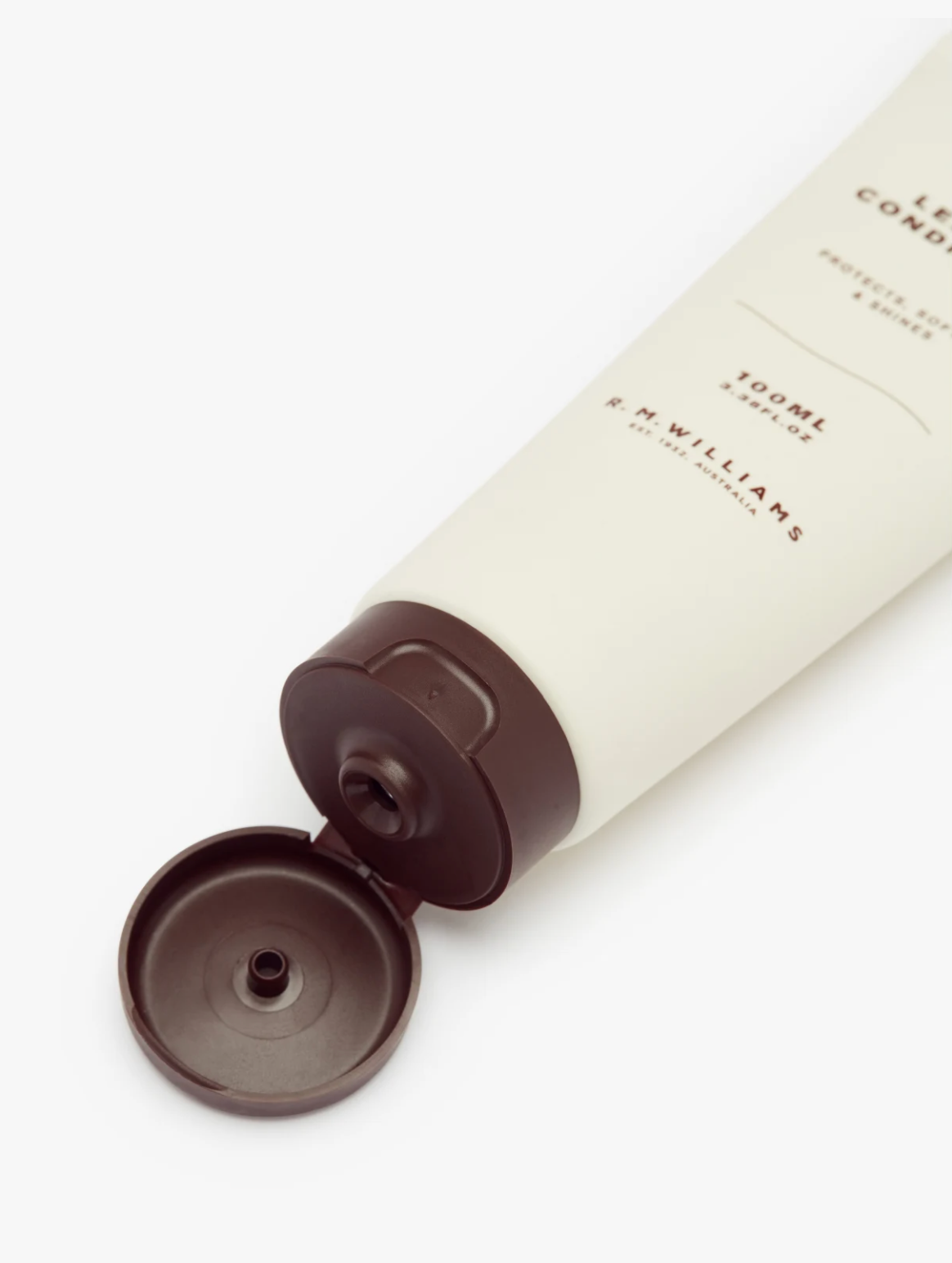 A 100 ml beige tube of RM Williams Leather Conditioner features a brown cap. The text on the tube reads, "LEATHER CONDITIONER - Protects, softens & shines" and "100ml 3.38 FL.OZ." Crafted with premium Australian ingredients, it's ideal for maintaining your leather boots. The label also states, "R.M.WILLIAMS - Est. 1932, Australia.