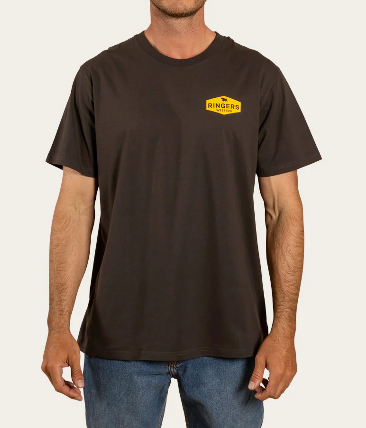 Against a plain background, a person sports blue jeans and a Ringers Western Servo Loose Fit T-Shirt in dark gray, featuring the iconic yellow logo on the left chest.