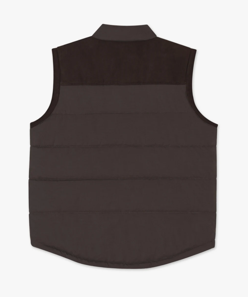 The RM Williams Carnarvon Vest is a dark brown, sleeveless garment featuring a quilted pattern, a collared neck, and a slightly curved hem. The upper back area showcases a darker brown yoke. This lightweight, puffer-style vest is perfect for trans-seasonal dressing and ideal for layering.