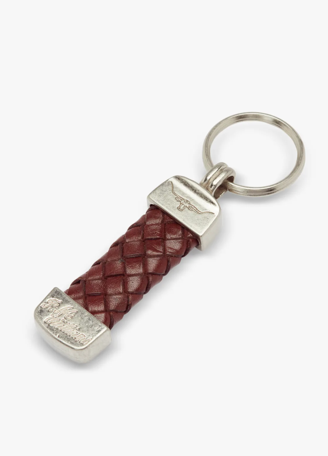 The RM Williams Plaited Key Ring features a silver ring and ends, a maroon braided Kangaroo leather section, and Longhorn embossed designs on the silver ends, adding an elegant touch to its overall look.