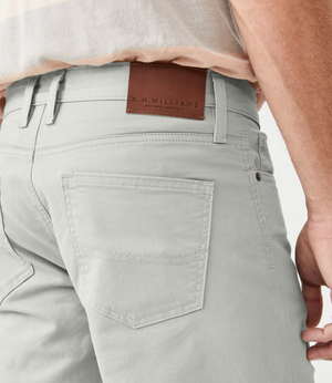 Close-up of a person wearing RM Williams Nicholson Short in light grey, featuring a brown leather patch embossed with "R.M. Williams" on the back waistband. The light-colored shirt is neatly tucked in, showcasing the classic 5 pocket styling for a tidy appearance.