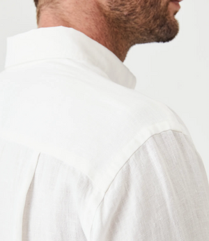 Close-up of a man in the RM Williams Coalcliff Shirt, a white linen long sleeve with collar. The lightweight, textured fabric is visible from the back view, showing part of his face and neck against a plain light background.