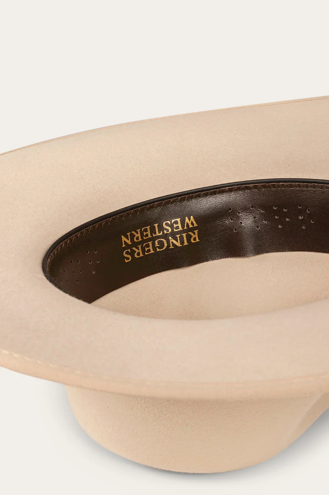 Close-up of the Ringers Western Woodford Hat, a premium felt cowboy hat with a wide brim. Inside, it features a dark brown band with "RINGERS WESTERN" in gold letters and is complemented by a sleek grosgrain ribbon.