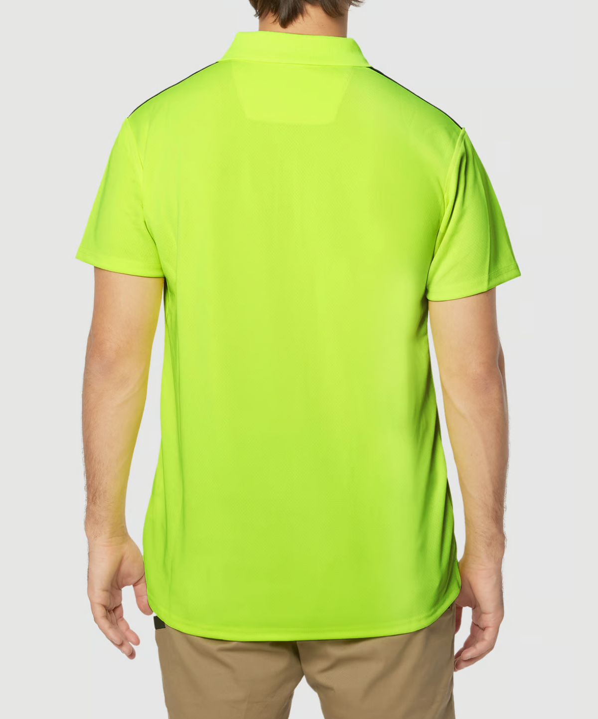 A person is shown from the back wearing a CAT Hi Vis Performance Polo in bright neon green, featuring short sleeves and moisture control fabric, paired with light brown pants against a white background.