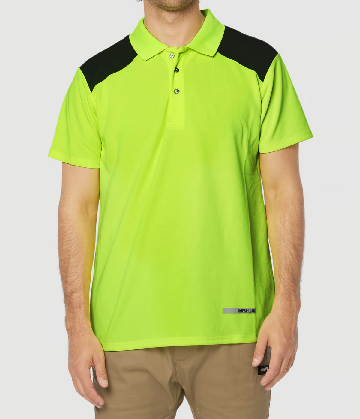 A person is wearing a fluorescent yellow CAT Hi Vis Performance Polo with black shoulder panels and beige pants. The moisture control shirt features a small logo on the lower front, set against a plain white background.