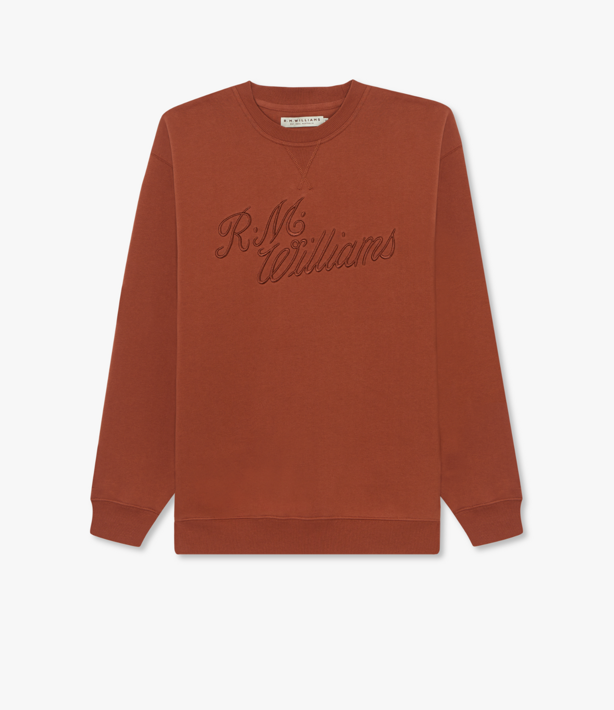 The RM Williams Script Crew Neck is a rust cotton-blend jumper with ribbed cuffs and hem, featuring "R.M. Williams" cursive embroidery on the chest for comfort and classic style.