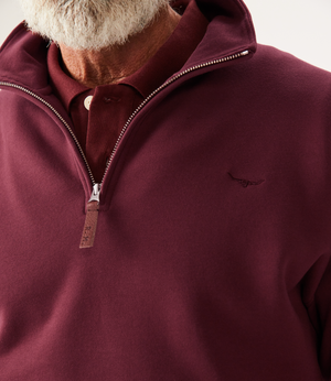 A man with a white beard wears an RM Williams Mulyungarie Fleece quarter-zip sweatshirt in maroon over a matching polo. The brushed cotton fleece has a small embroidered chest logo. Only his lower face and upper torso are visible.