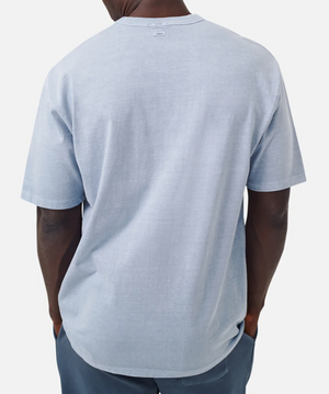 A person with short hair, wearing the Industrie The Del Sur Tee in light blue and dark pants, is seen from behind against a plain white background.