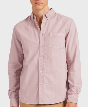 A person is wearing the Academy Brand Vintage Oxford Shirt in light pink, featuring a refined point collar and crafted from 100% Cotton Oxford. The shirt has a relaxed fit, is buttoned to the collar, and is paired with khaki pants against a plain white background.