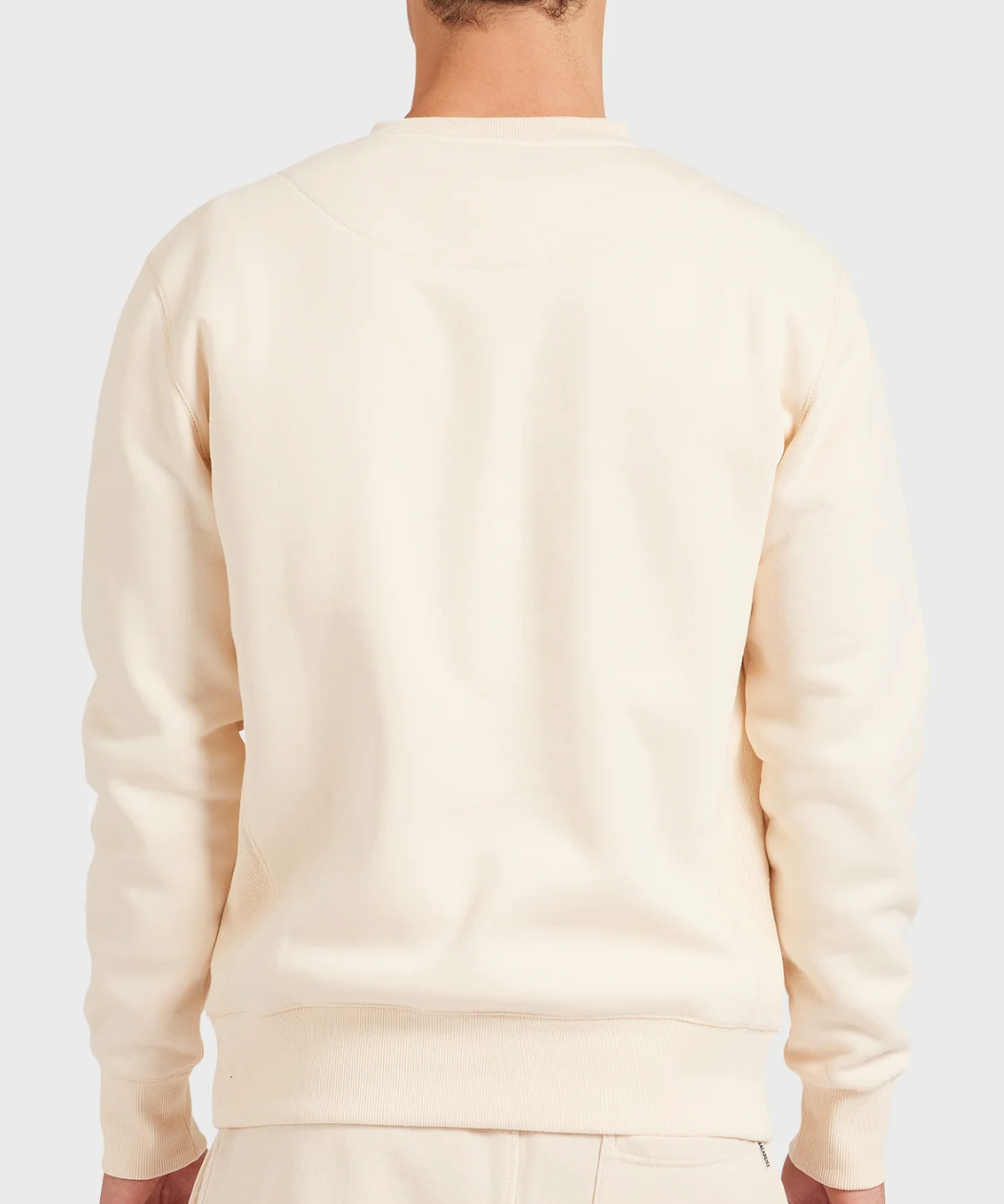 A person is shown from the back against a light gray background, wearing the Academy Brand Crew Sweat in cream with matching relaxed fit brushed fleece pants.