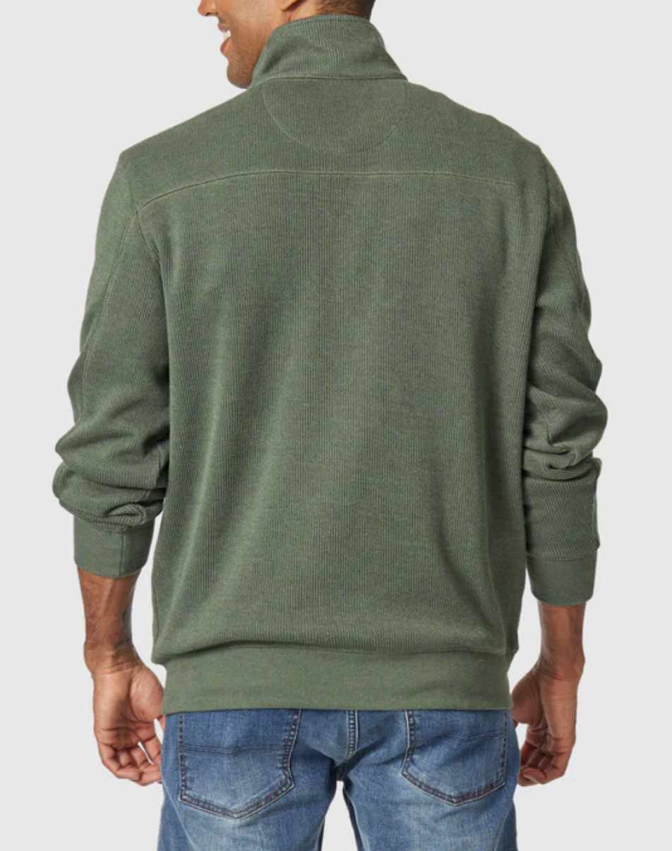 A man is seen from the back, arms relaxed at his sides, wearing the Blazer Heather Half Zip Sweat in green with blue jeans.