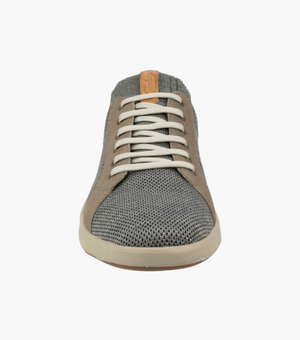 The Florsheim Crossover Knit is a casual low-top sneaker with a gray knit upper for breathability, light brown suede accents, and white laces. It has a cushioned footbed on a white sole and features a tan leather strip on the tongue.