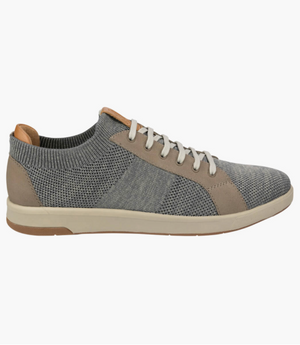 The Florsheim Crossover Knit is a casual grey sneaker featuring a breathable knit upper, light grey laces, beige leather accents, and a cushioned footbed on a white rubber sole. It showcases varying shades of grey in a subtle pattern for enhanced style and comfort.