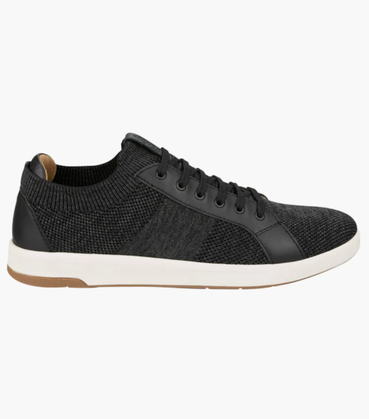 The Florsheim Crossover Knit is a black low-top sneaker with a textured mesh design and knit elements. It features black laces, smooth accents, a cushioned footbed for comfort, and is finished with a white midsole and brown rubber outsole for an elegant, modern look.