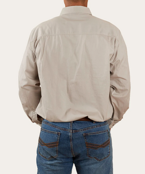 A person wearing the Ringers Western King River Half Button Shirt in beige, paired with blue jeans, is facing away from the camera with hands in pockets. The background is plain and light-colored.