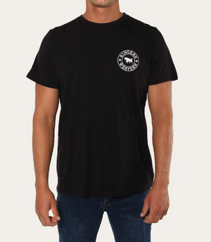 A person wearing a comfortable, pre-shrunk cotton Ringers Western Signature Bull Classic T-Shirt, which features a small white logo and the text "Ringers Western" on the upper left chest. The person is also wearing blue jeans against a plain white background.