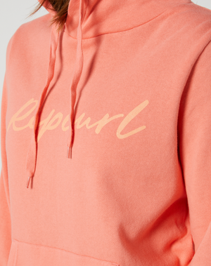 Close-up of a person wearing a comfortable coral-colored Rip Curl Script II Hood with "RapcurL" printed in yellow script across the chest. This casual hoodie features a front pocket and visible drawstrings, perfect for laid-back days.