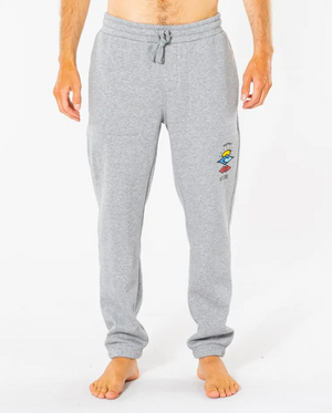 A person is barefoot against a white background, showcasing only the lower half while wearing Rip Curl Search Icon Track Pant in gray. The pants feature a colorful patch on the left thigh and an elastic waist for comfort, made from Organic Brushed Cotton.