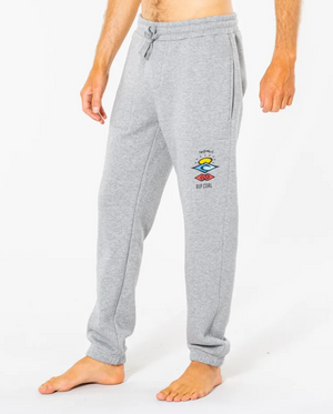 A person in light gray Rip Curl Search Icon Track Pants with a colorful logo on the left thigh, made of organic brushed cotton, featuring an elastic drawstring waist, stands barefoot against a plain white background.