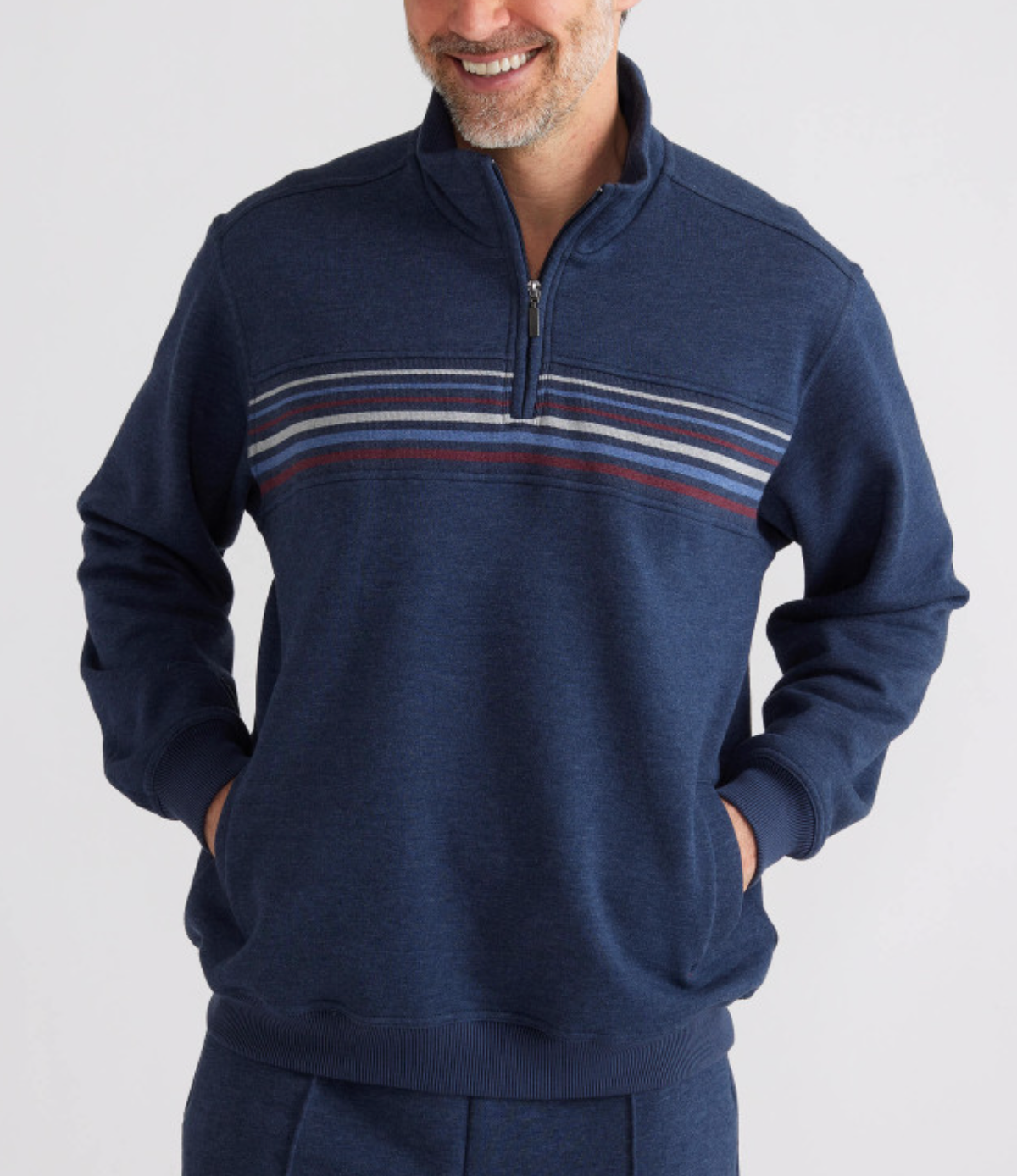 A person is cozy in the Breakaway Huxter Snowy Mt Fleece 1/2 Zip, dark blue with a horizontal stripe pattern. Their hands rest comfortably in the pockets as they smile against a plain white background.
