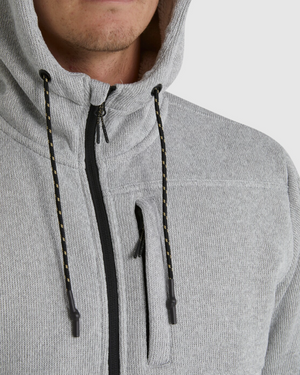 A close-up shows someone wearing the Billabong Boundary Sherpa Zip hoodie in light gray with black zipper details and drawstrings, revealing only the lower half of their face and upper torso.