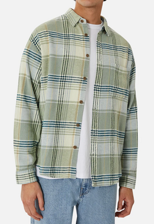 A person wears the comfortable Industrie The Anderson Shirt in green and white plaid, layered over a crisp white T-shirt, paired with light blue jeans for an effortlessly stylish look.
