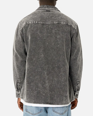 A person is wearing the comfortable Industrie The Duster Jacket in a faded black hue over a white shirt and light blue jeans. Made from 100% cotton, the jacket features a casual, worn look with buttoned cuffs. The person is shown from the back against a plain white background.