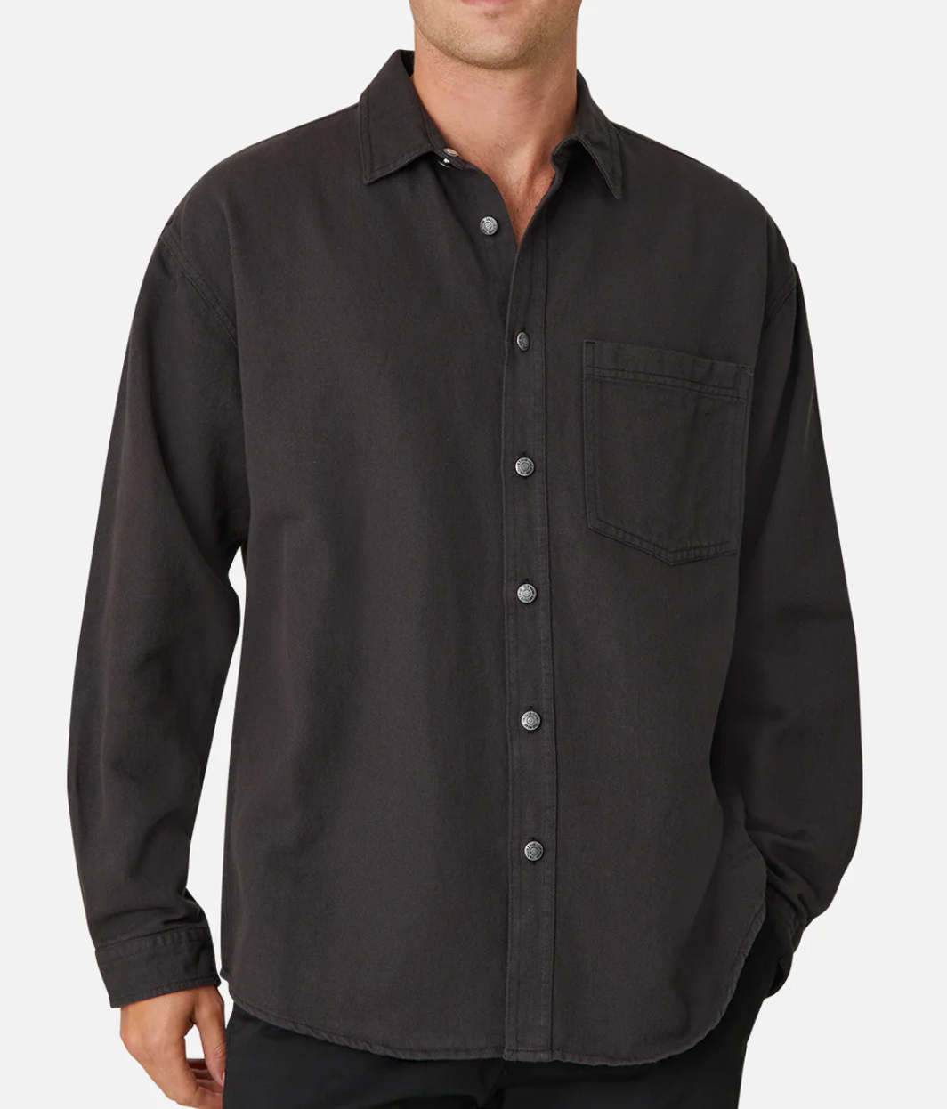 A person wearing the Industrie The Portland Shirt—a stylish, relaxed fit, dark grey cotton/linen long-sleeve button-up with a front chest pocket and Industrie logo—stands against a plain white background. Sleeves are unrolled.