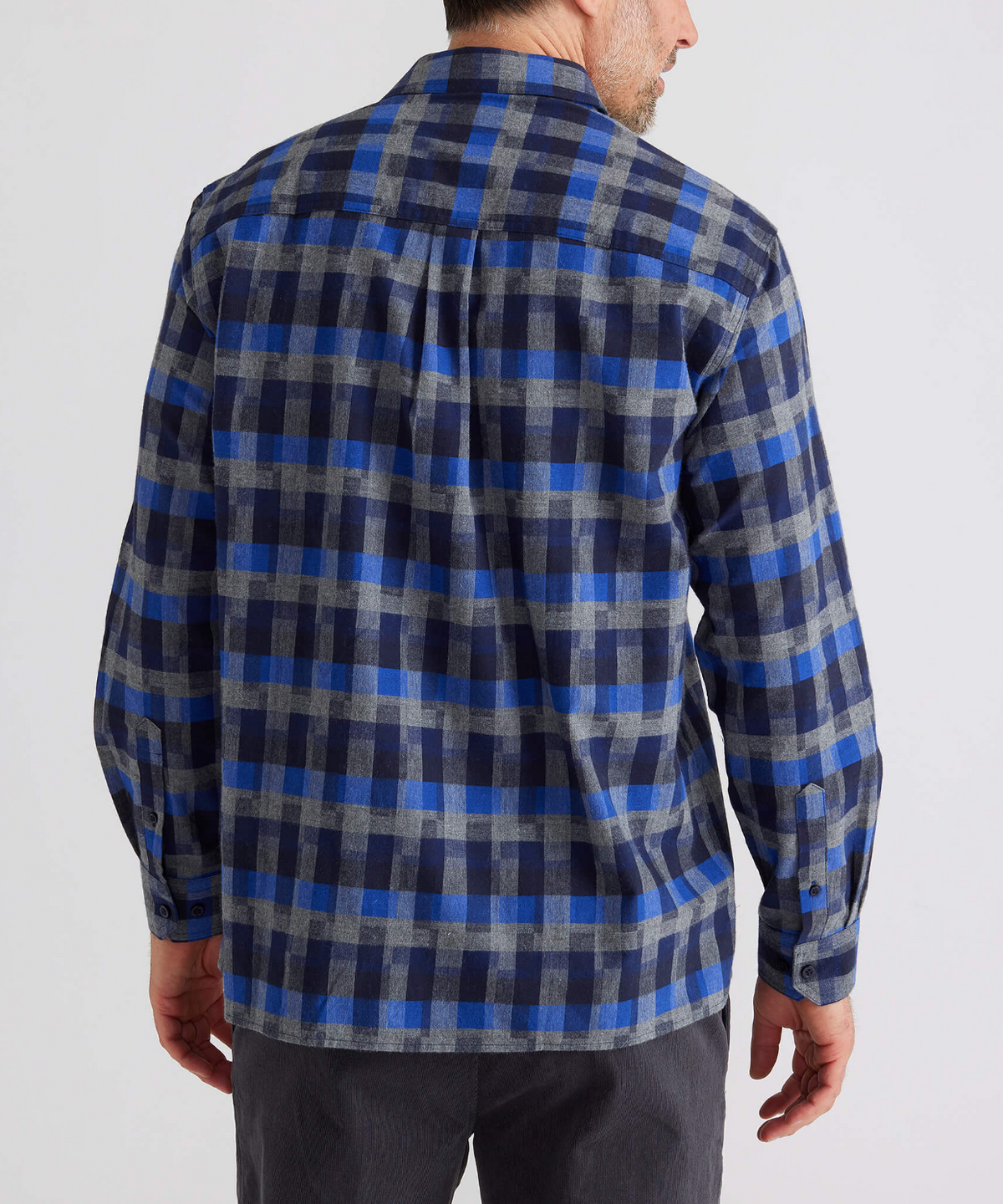 A person is wearing the Breakaway Benny Cotton Brush Shirt, a long-sleeved blue and gray checkered flannel made of brushed cotton, seen from behind with a casual, relaxed fit. It's paired with dark pants against a plain white background.