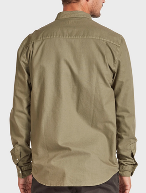 A person is pictured from behind wearing the Academy Brand Vintage Oxford Shirt, a collared, long-sleeved button-up in an olive-green hue. The stylish and slightly wrinkled shirt exudes a casual vibe as the person's arms rest relaxed at their sides against a plain, light-colored background.