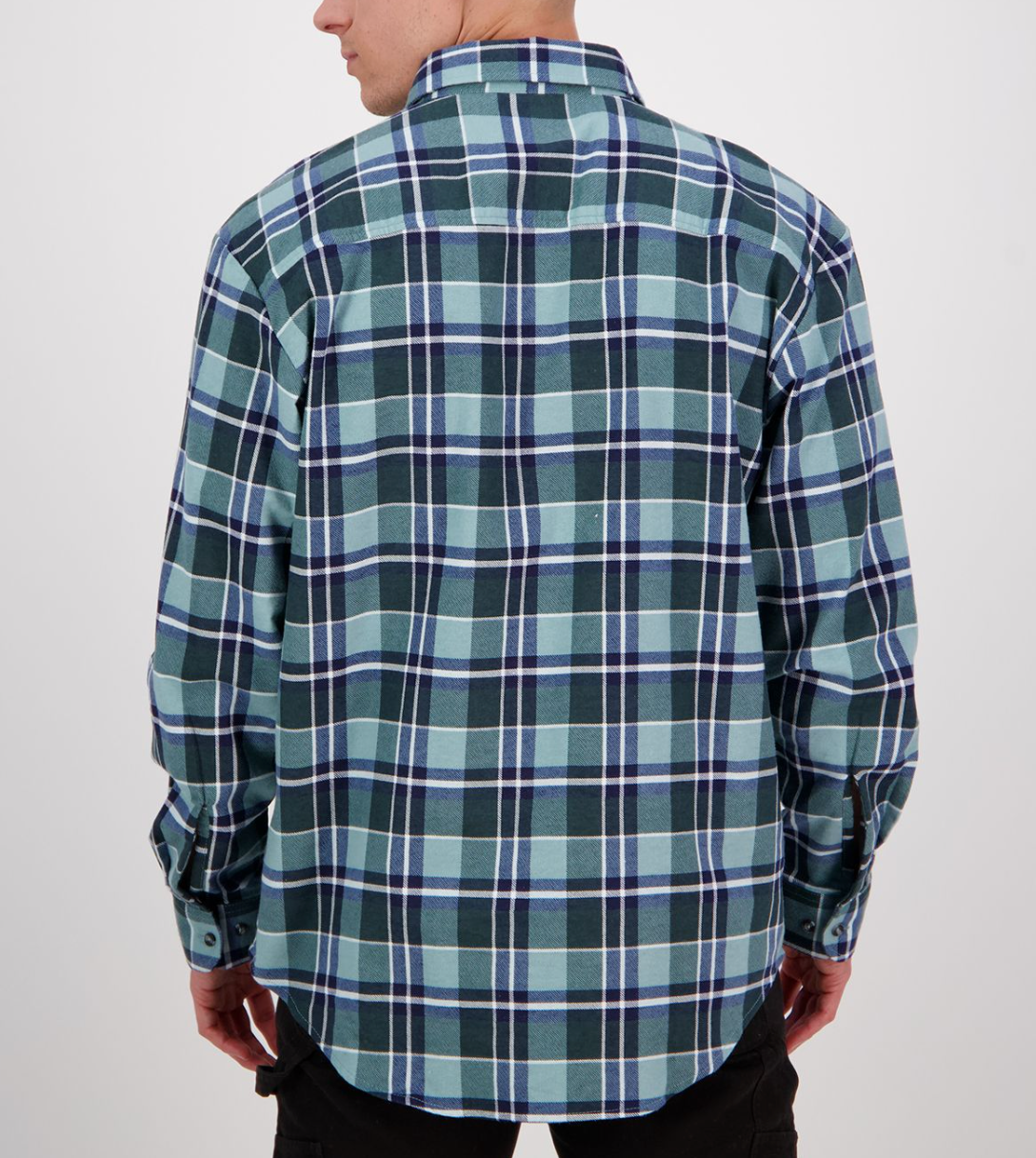 A person facing away from the camera is wearing a Swanndri Egmont Flannelette Twin Pack, featuring a long-sleeved, blue and green plaid shirt crafted from brushed cotton. The classic design with dark stripes is paired with dark pants.