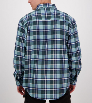 A person facing away from the camera is wearing a Swanndri Egmont Flannelette Twin Pack, featuring a long-sleeved, blue and green plaid shirt crafted from brushed cotton. The classic design with dark stripes is paired with dark pants.