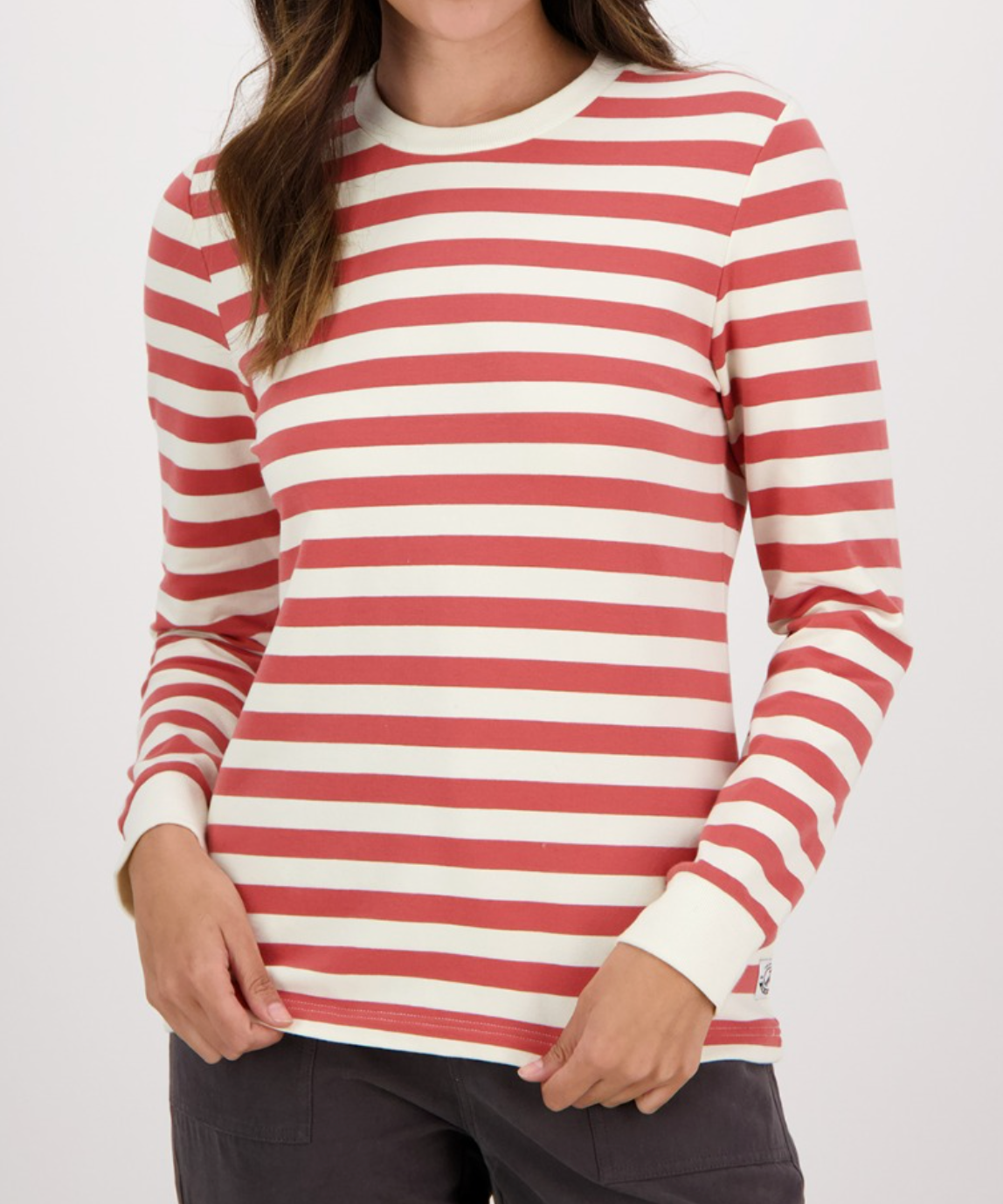 The person wears a Swanndri Papamoa Stripe Long Sleeve Tee, striped in red and white with a crisp collar, crafted from heavy weight fabric, paired with dark pants. The image focuses on the upper body with the head partially cropped out.