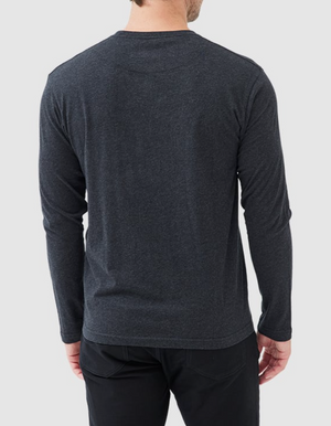 A person in a dark gray Rodd & Gunn Long Sleeve Gunn T-Shirt, made of 100% cotton, and black pants faces away from the camera against a light gray background. The sports fit adds a relaxed vibe, ideal for casual settings.