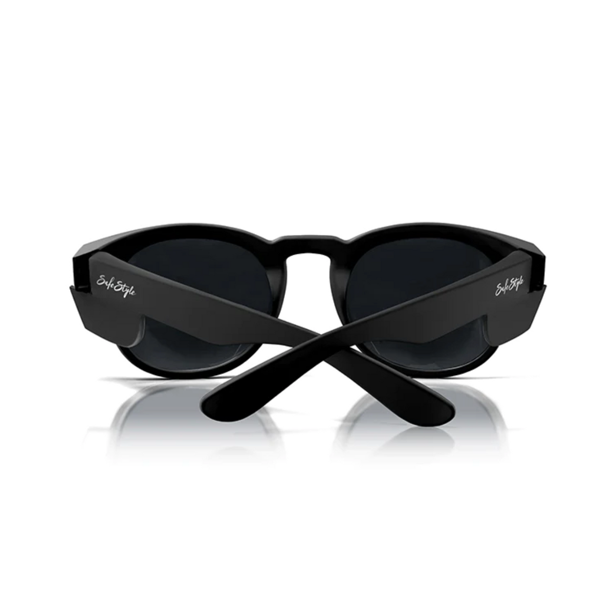 A pair of SafeStyle Cruisers matte black frame sunglasses with dark, polarised lenses, viewed from the back with the arms crossed. The brand name "SubStyle" is written in white on both arms. The sunglasses are positioned on a reflective white surface.