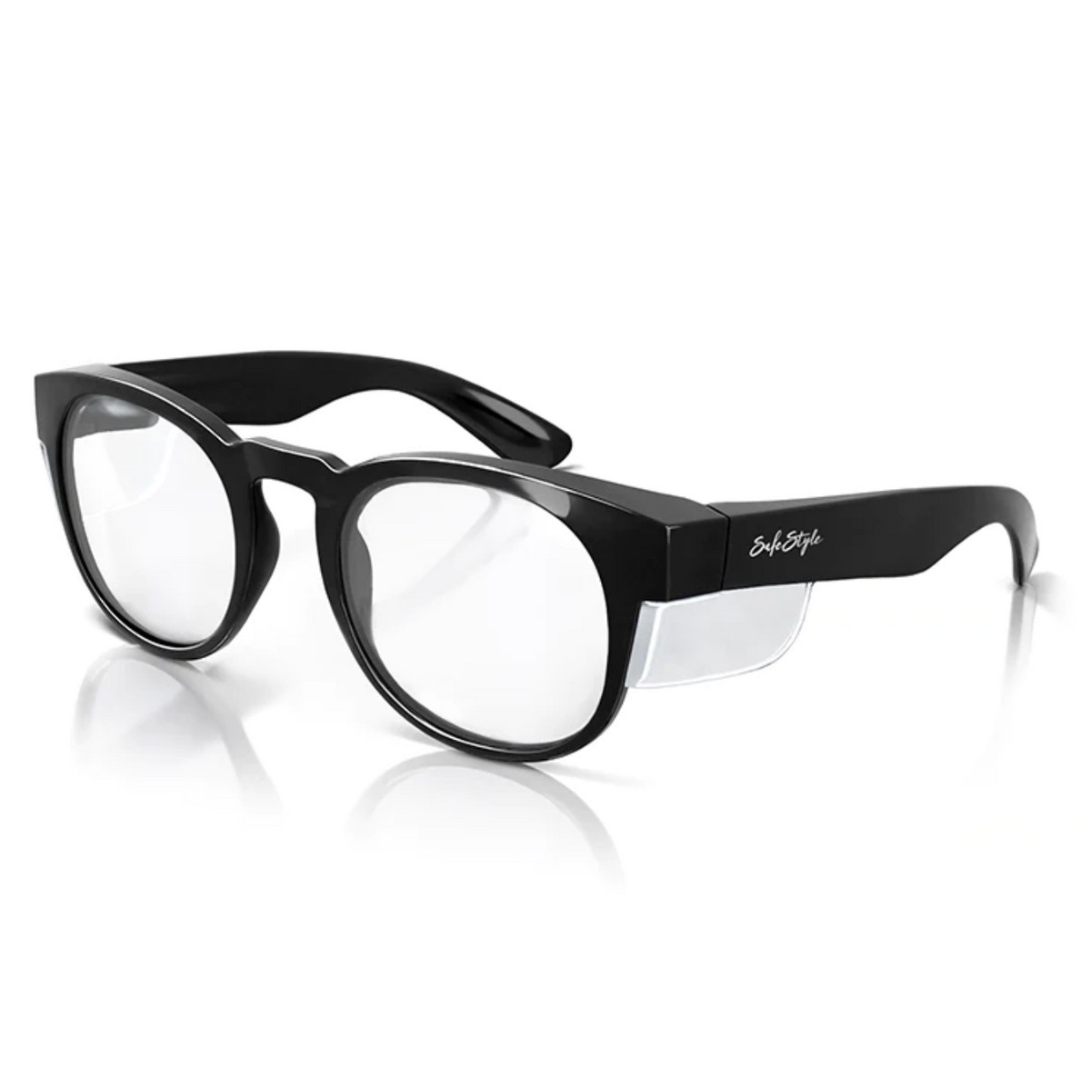 SafeStyle Cruisers Black Frame Clear Lens glasses offer excellent UV protection with high safety ratings, featuring side shields and logoed temples. Resting on a white reflective surface, they showcase a sleek design.