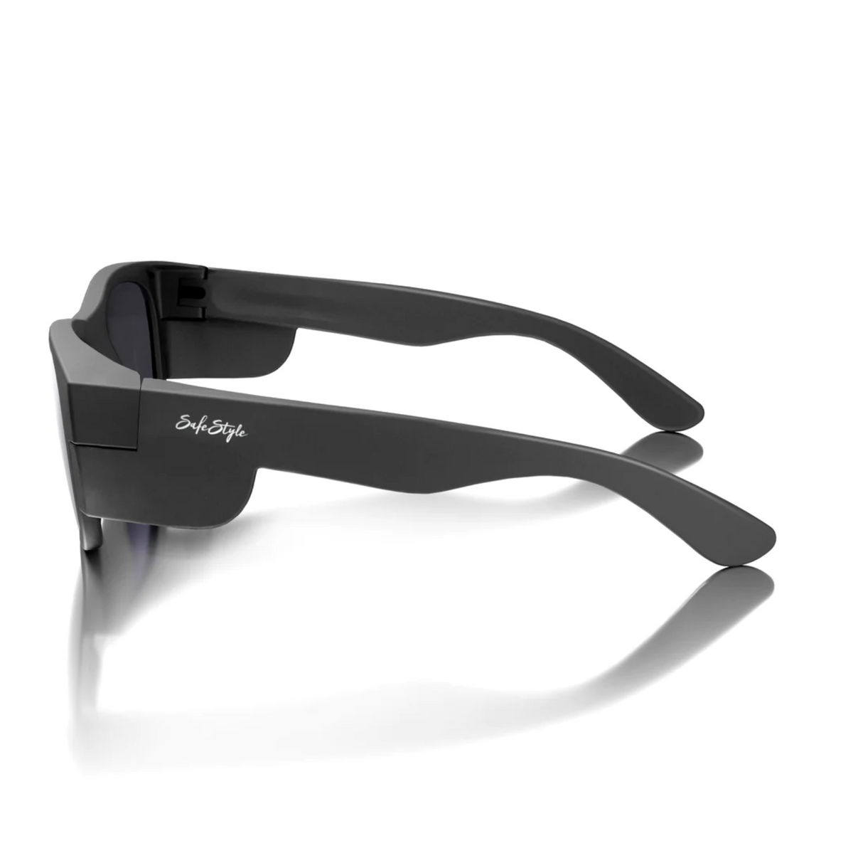 Side view of SafeStyle Classics sunglasses with matte black thick frames and polarised lenses for UV protection, reflecting on a white surface. A small white logo is on the arm.