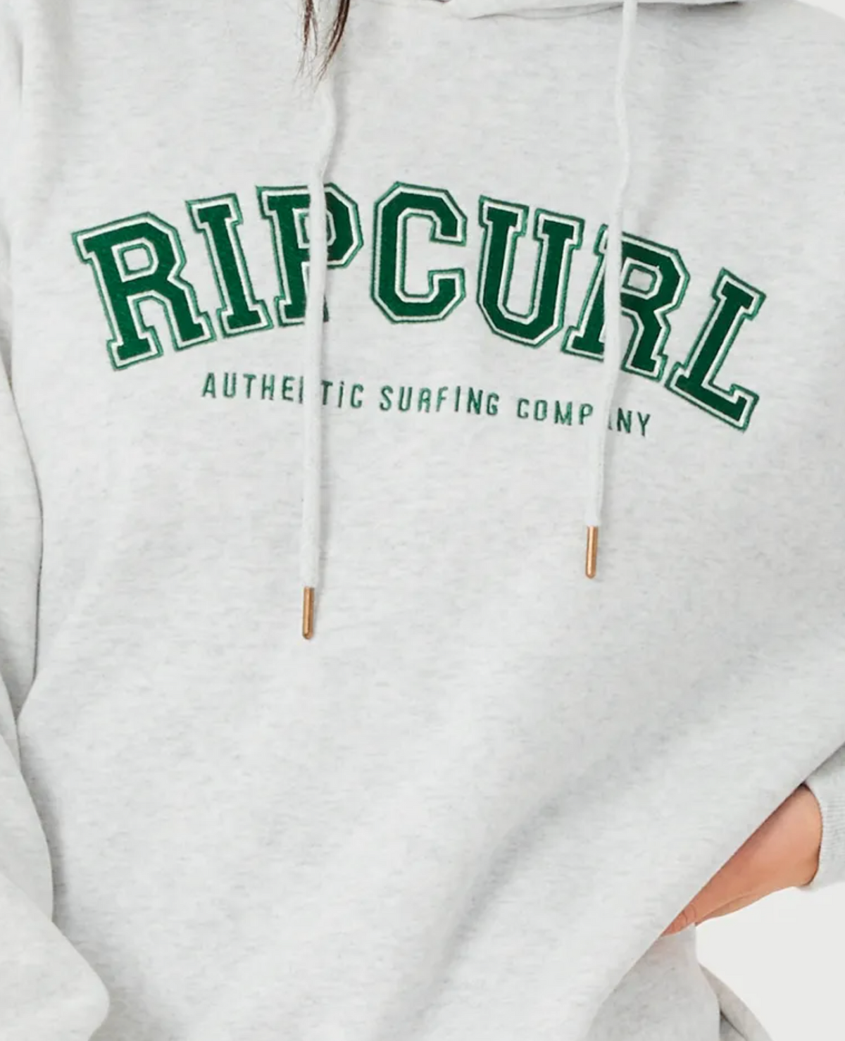 Close-up of a relaxed fit gray Rip Curl Varsity Hoodie with bold green "RIP CURL" above "AUTHENTIC SURFING COMPANY"; features white drawstrings with gold tips and cozy fleece lining for style and comfort.