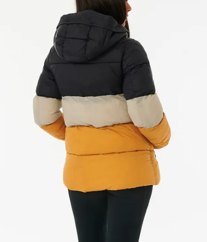A person wears a Rip Curl Anti Series Insulated II Jacket. This color-blocked design in black, beige, and orange features a hood. Paired with dark pants on a white background, this DWR water-repellent piece combines style and functionality to keep you dry.