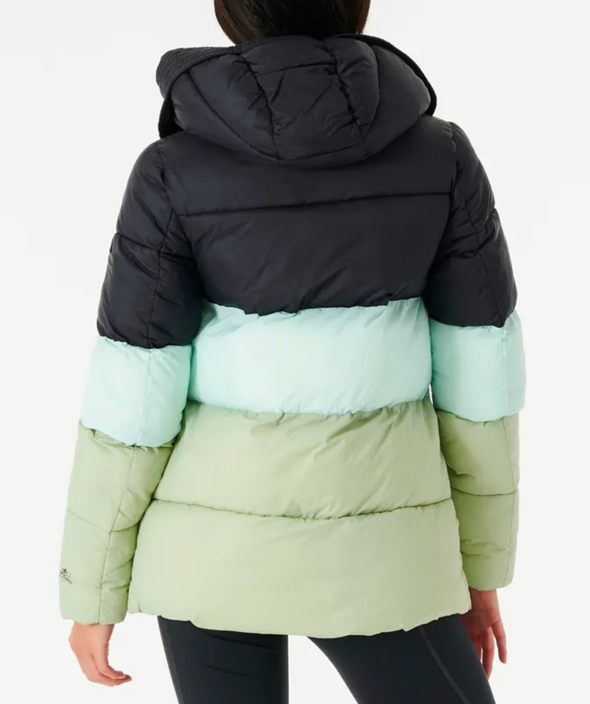 Rear view of a person wearing the Rip Curl Anti Series Insulated II Jacket with black, light blue, and light green color-blocking. The water-repellent puffer pairs well with black leggings. The person, with long hair, stands against a plain white backdrop.
