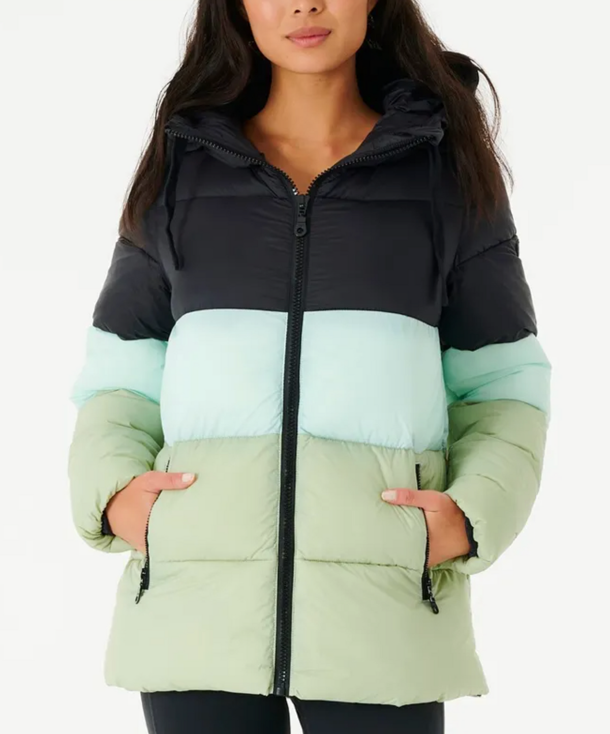 A person wears a Rip Curl Anti Series Insulated II Jacket, showcasing black, light blue, and green color blocks. The water-repellent puffer has a zipper and two front pockets where they tuck their hands, set against a plain white background.