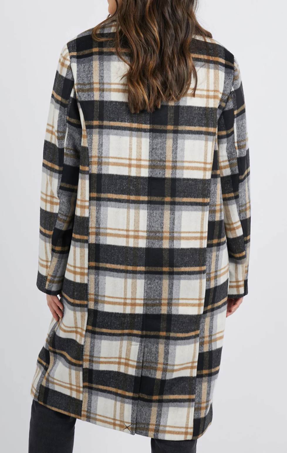 A person with long hair wears the Foxwood Catriona Coat, showcasing a stylish checkered plaid design in black, white, and brown tones against a plain white background.