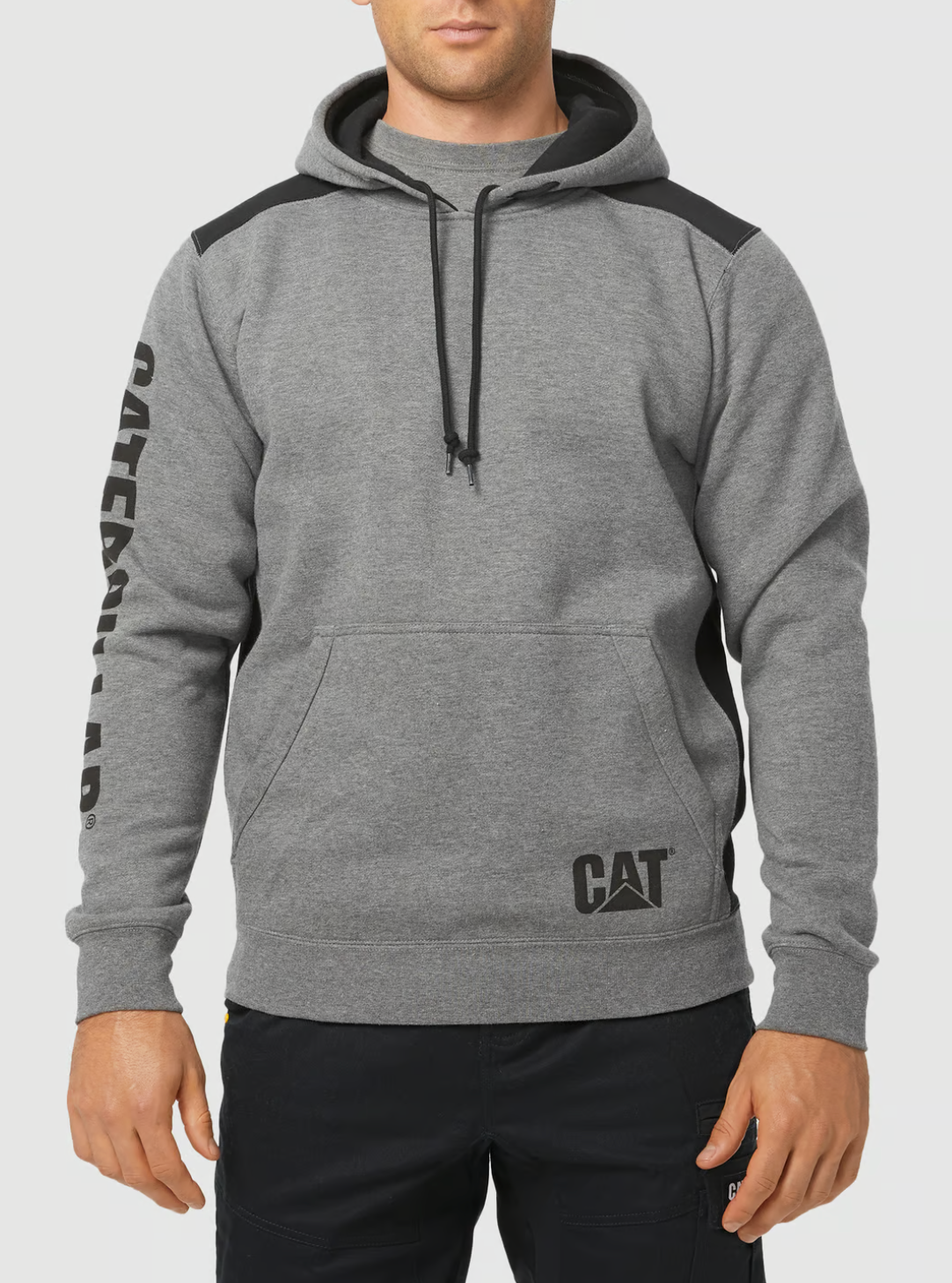 A person is wearing a gray CAT Logo Panel Hooded Sweat with "Caterpillar" on the sleeve, a CAT logo on the front, hidden Velcro phone pocket, black accents, and drawstring hood; paired with black pants.