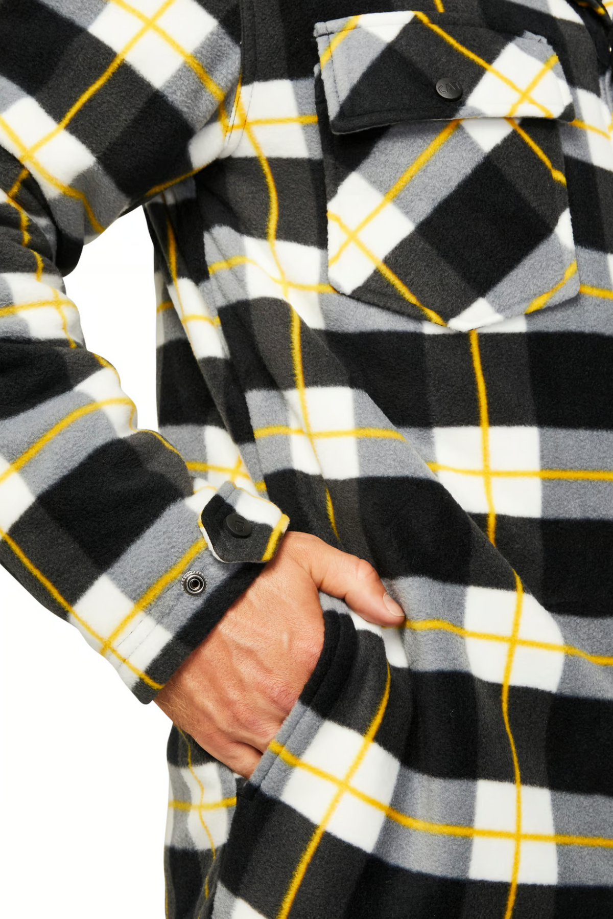 A person wearing the CAT Active Work Jacket in a black, white, gray, and yellow plaid pattern with chest pockets and adjustable cuffs places their right hand in a side pocket. Only their torso and hand are visible.