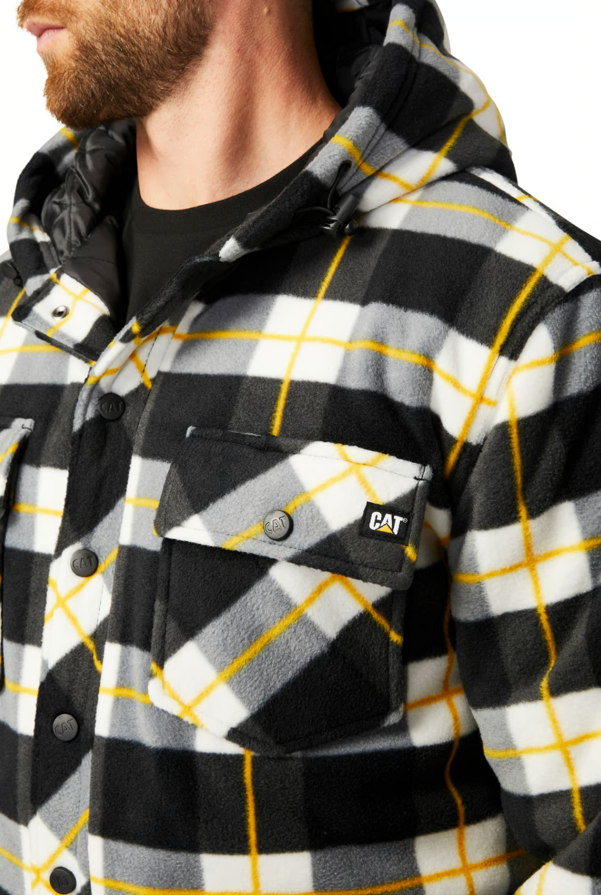 A man with a trimmed beard wears the CAT Active Work Jacket, featuring black, white, and yellow plaid fleece, an insulated hood, adjustable cuffs, button front, chest pocket with a "CAT" logo patch.