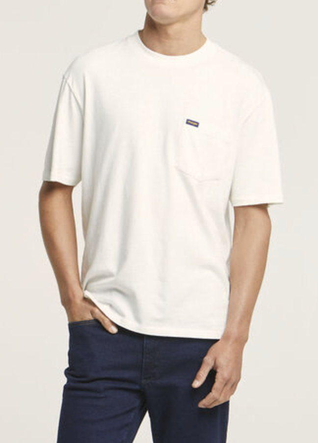 Someone stands with one hand in the pocket of their dark jeans, wearing a comfortable Wrangler Classic Pocket Tee made from 100% cotton, featuring a small logo on the chest pocket, against a plain background.