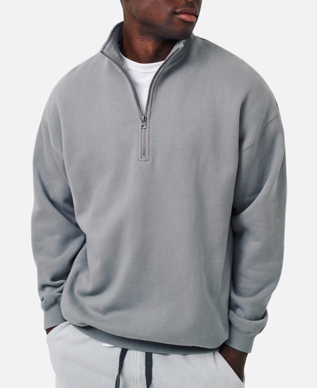 Wearing the Industrie The Del Sur Track Top in light gray, a person enjoys its oversized fit over a white shirt. Their hands are tucked into the pockets of matching comfy sweatpants, while the soft fleece lining enhances coziness against a plain white backdrop.