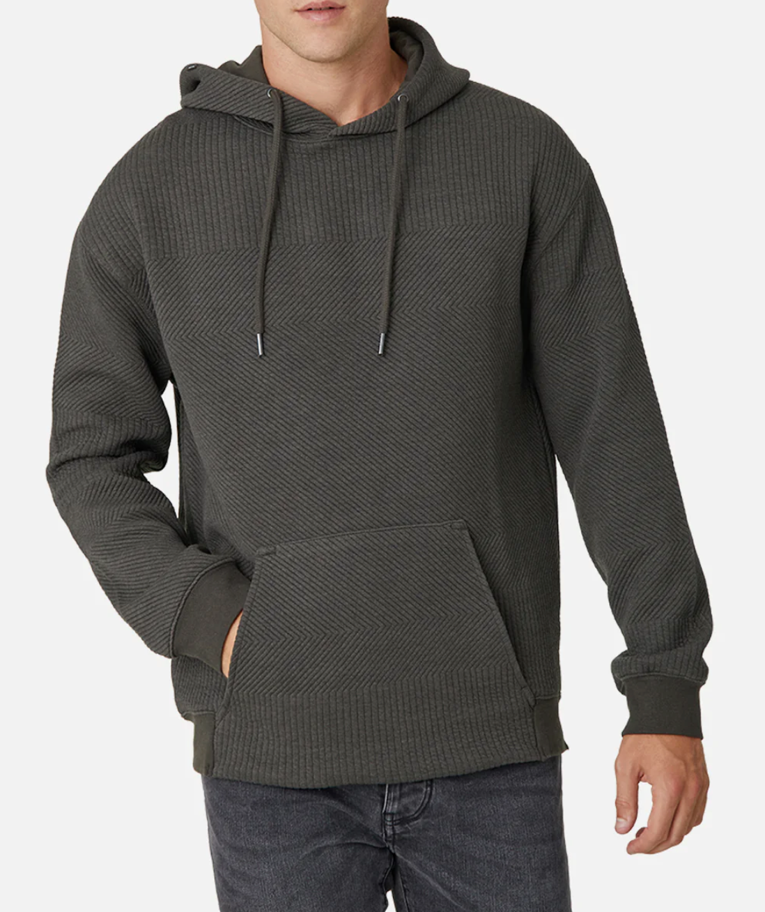 Wearing the Industrie The Robinson Hoodie in dark gray, this person showcases a relaxed fit with a textured design, complete with a front pocket and drawstrings. Paired with dark jeans, the outfit contrasts sharply against the plain white background.