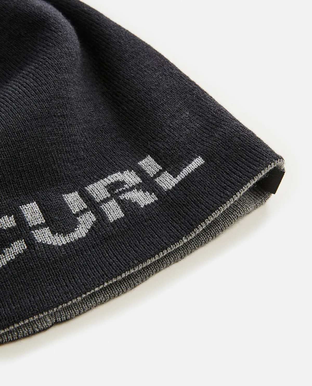 A close-up of a black Rip Curl Cutback Revo Beanie with partial white "URL" text near the edge, featuring a reversible design, displayed on a white background.