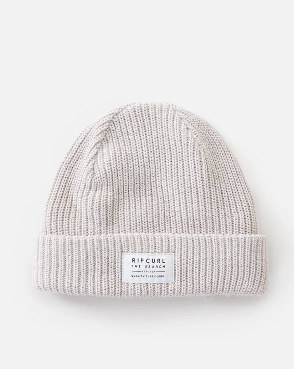 The Rip Curl Dusk Fleece Lined Regular Beanie features a light grey rib knit design, folded brim, and a front white rectangular label that reads "Rip Curl The Search." It is displayed flat against a plain white background.